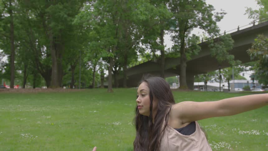 A woman dances in the grass at a park