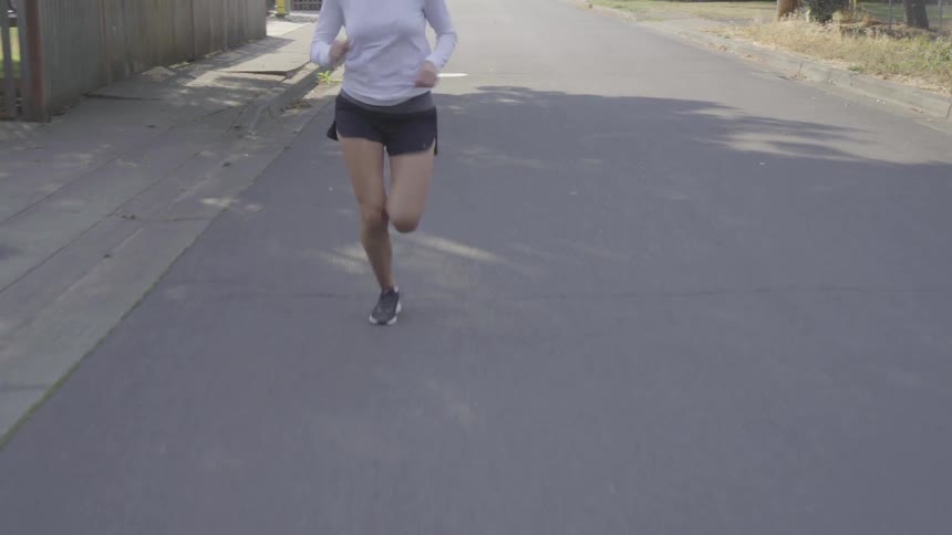 A young female jogging in a suburban street on a sunny day