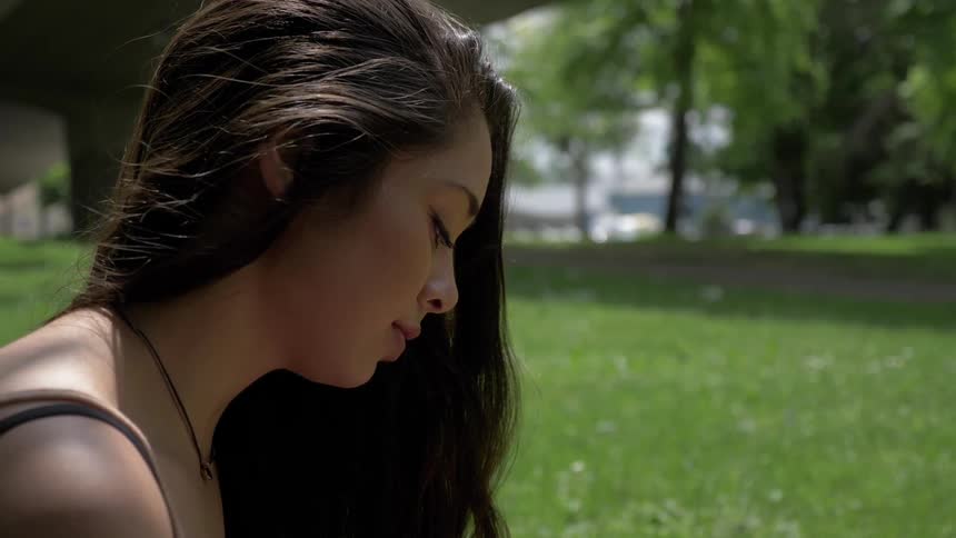 A woman sits in the grass looking down
