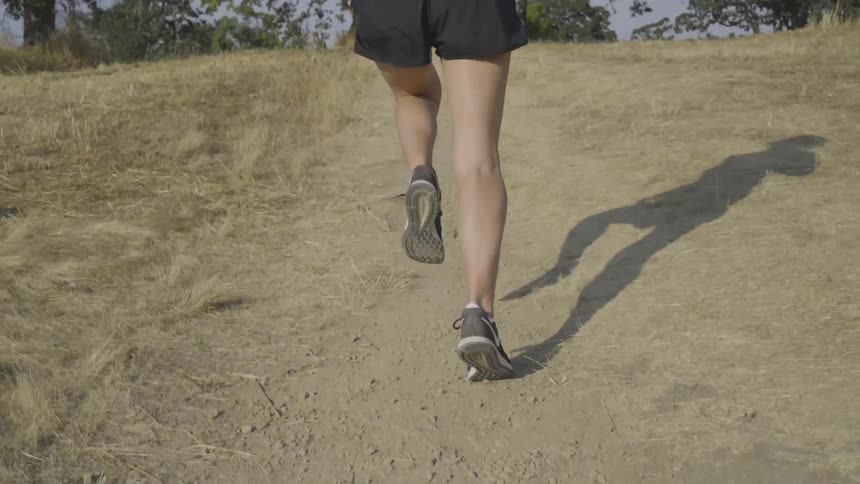 A white woman runs up a dirt path