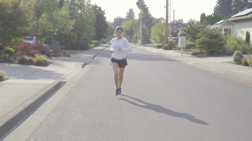 A woman runs down a street in a residential area