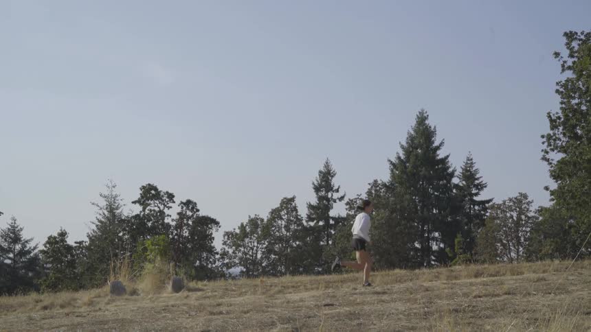 A white woman runs across a grassy field