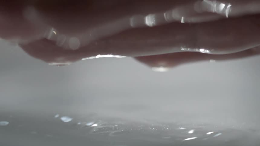 A person lifts their hands out of the water