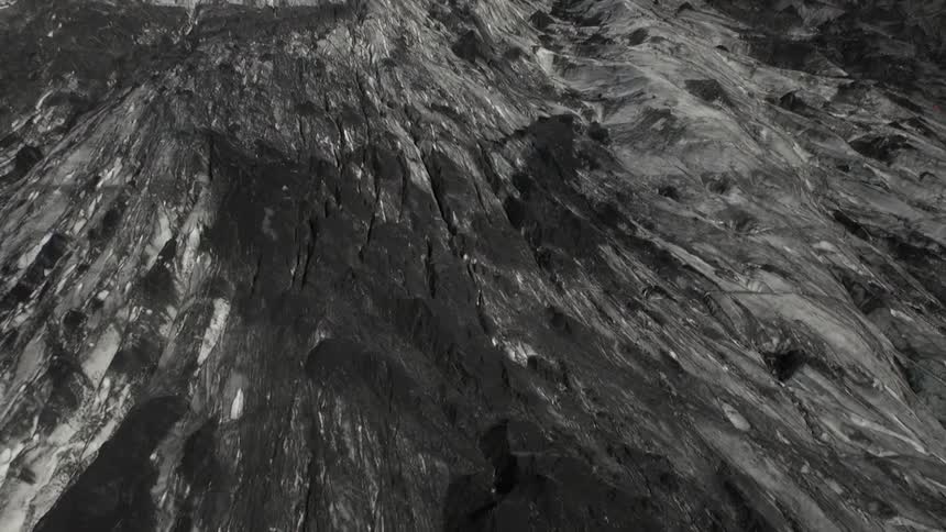 Overhead view of a rocky mountain top and other mountains in the distance