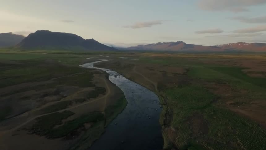 A stream winds through the plains leading to mountains