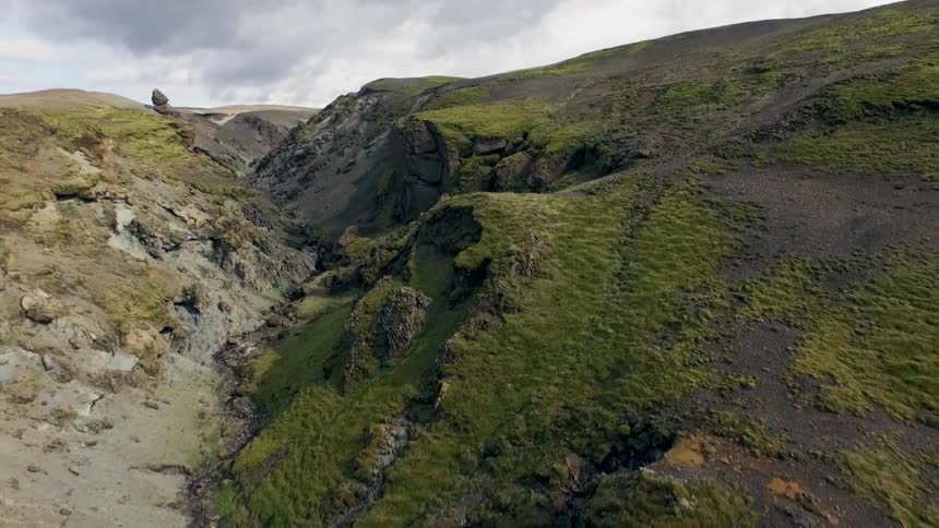 Aerial view passing over rocky cliffs to show a deep crevice