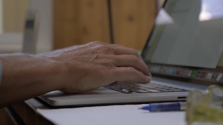 A person types on a laptop and uses the touch pad