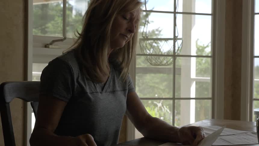A woman reading a letter at a table and marking it