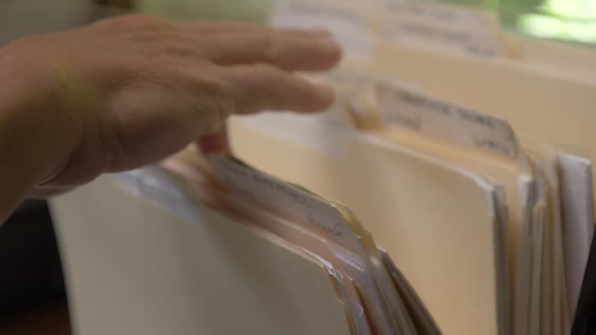 A person searching through manila folders