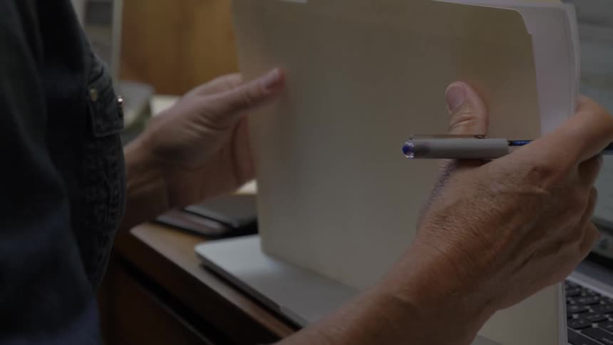 A person writing on a paper then filing it away