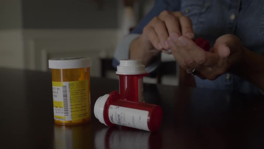 A woman gets a pill from a prescription bottle and takes it dry