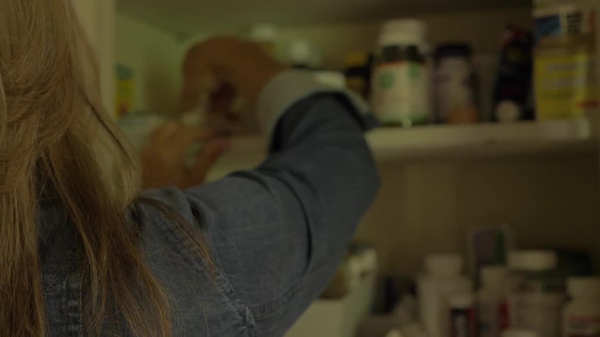 Woman opening a cabinet looking for medicine