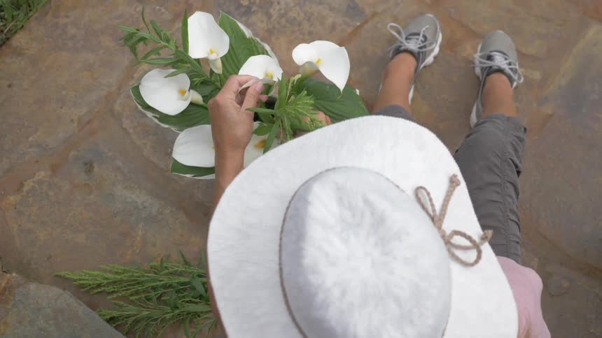 Woman arranges flowers while wearing a sun hat