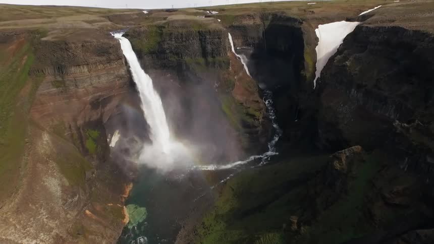Water falls down a tall cliffside on a sunny day