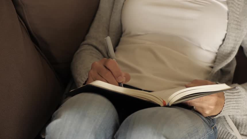 A female sits and writes in a book