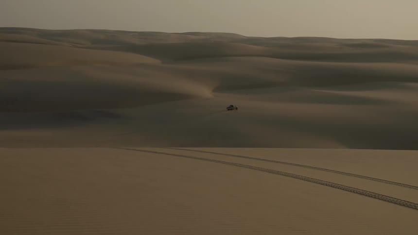 A truck driving through a sandy desert