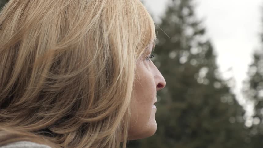 A middle aged woman looks into the distance pensively