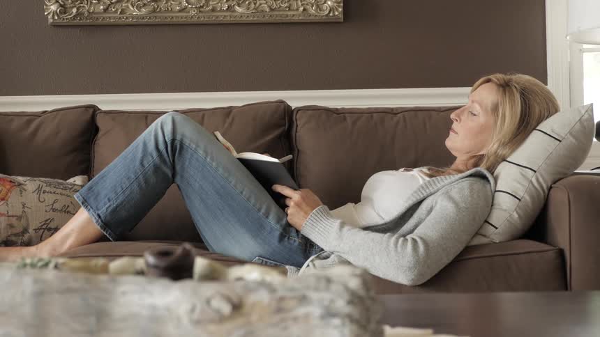Woman lays on the couch writing in a journal