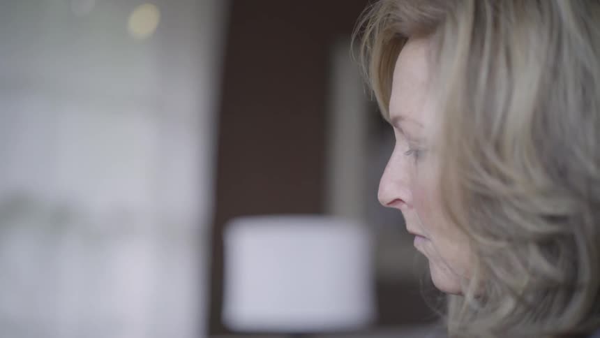 A woman stares downwards in an indoors environment