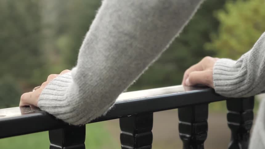 A person holds on the a balcony railing