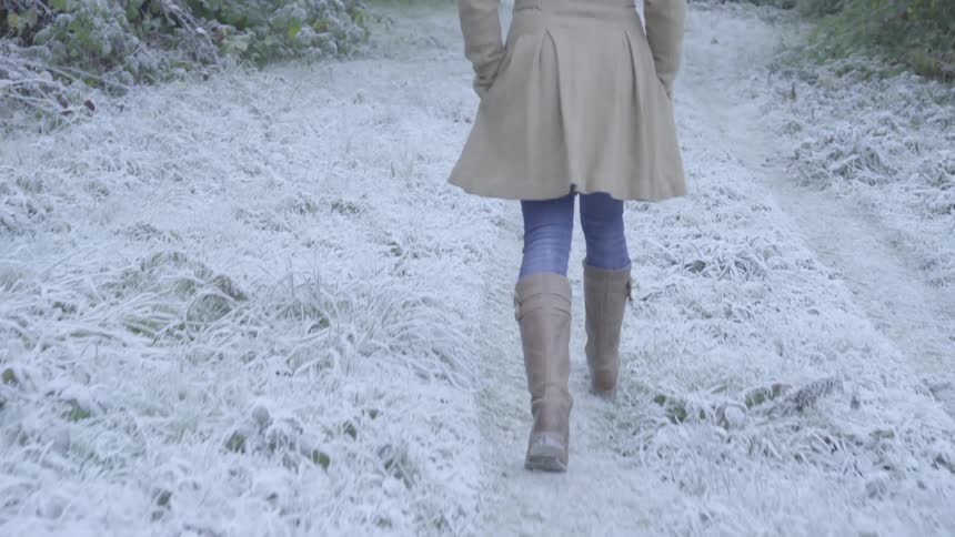 A woman walks along a snow covered path in the woods