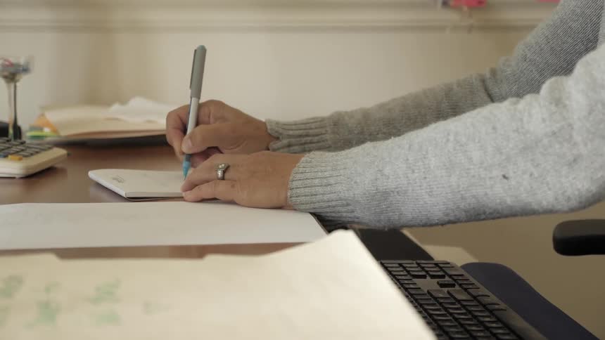 Person types on keyboard while sitting a desk then writes a note