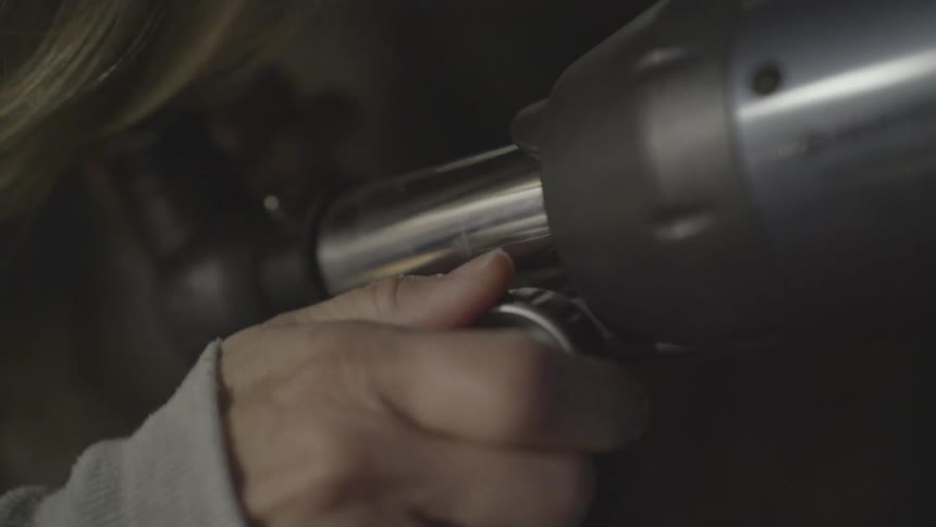 A woman spins the dial on a telescope