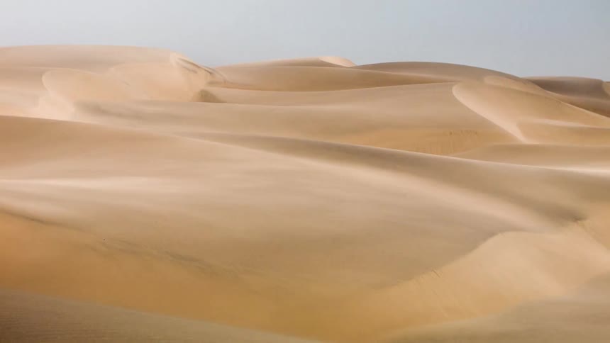 Wind blowing over sand dunes on a sunny day