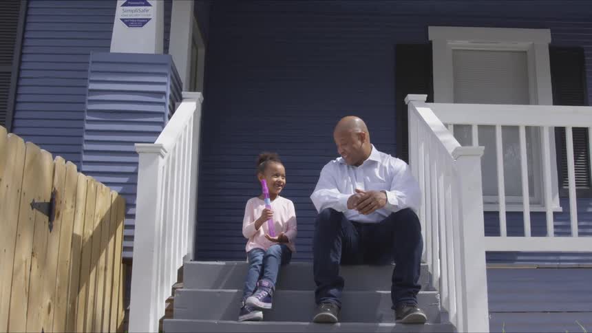 Man and a girl sit on a porch talking with each other