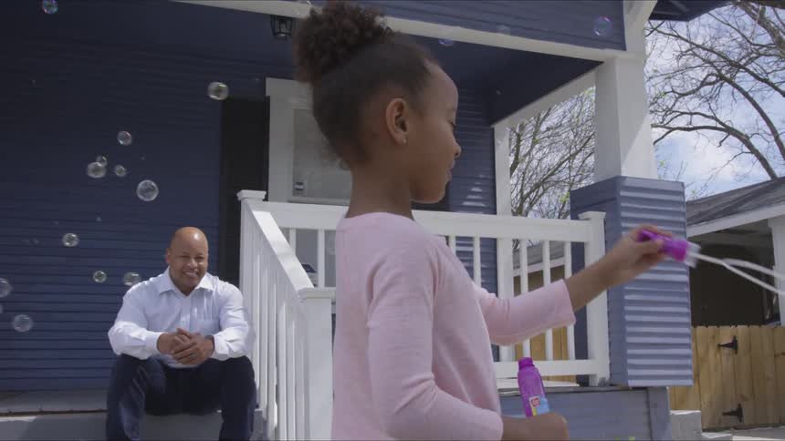 Child plays with bubbles outdoors while dad watches from steps