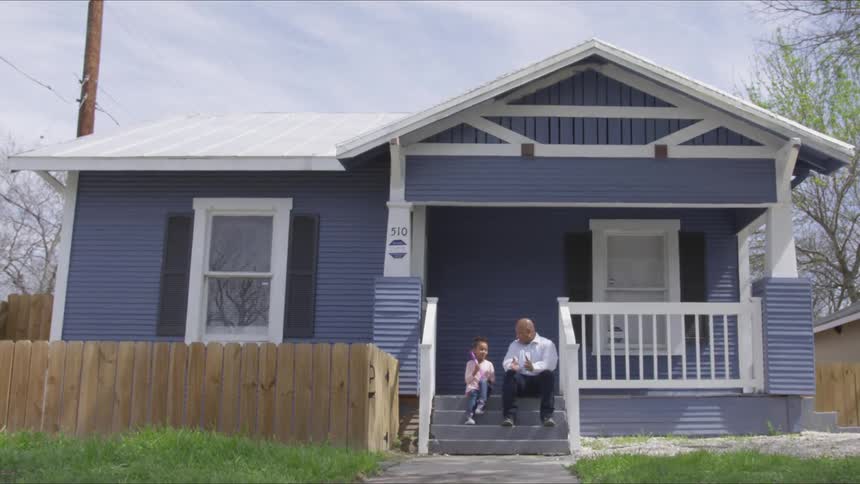 A man and child sit on the steps of a home talking