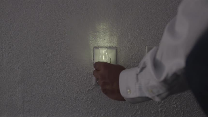 A man plugs a night light into a power outlet