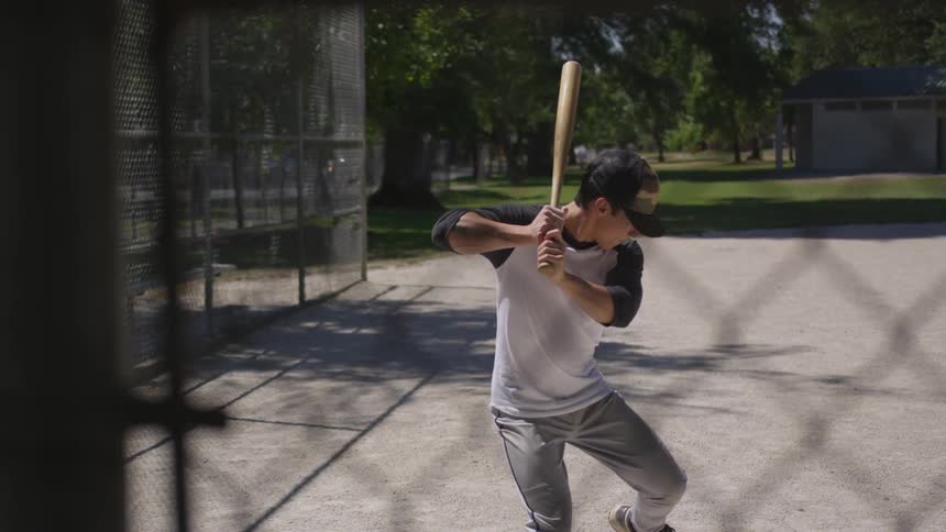 A man takes a practice swing with a baseball bat