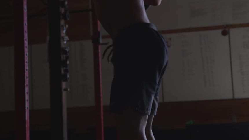 Half naked man works out in dim light gym