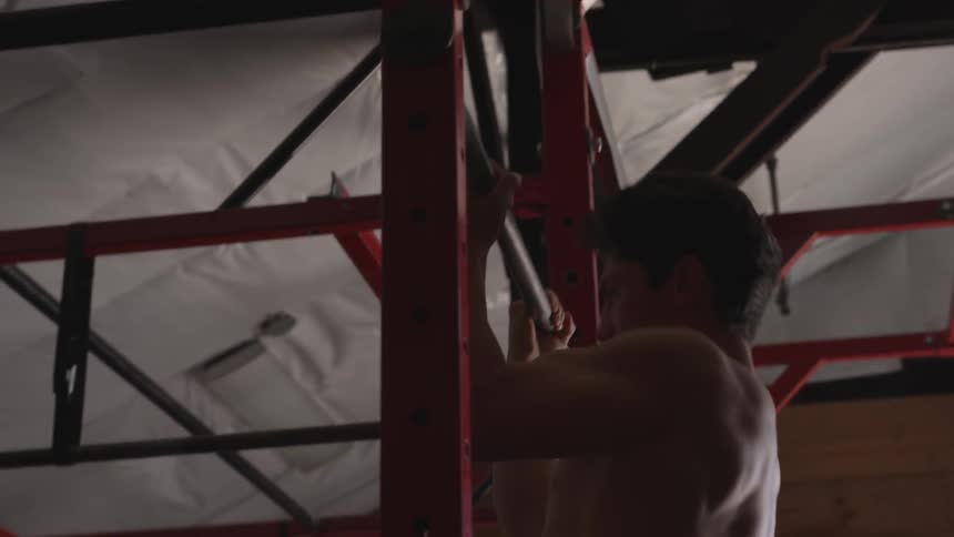 A white man does pull ups on a metal bar