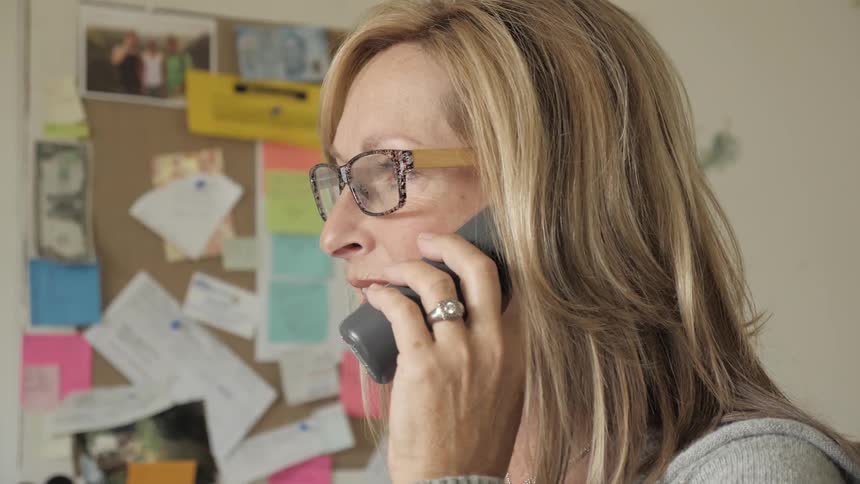 A woman wearing eyeglasses taking on a cordless phone