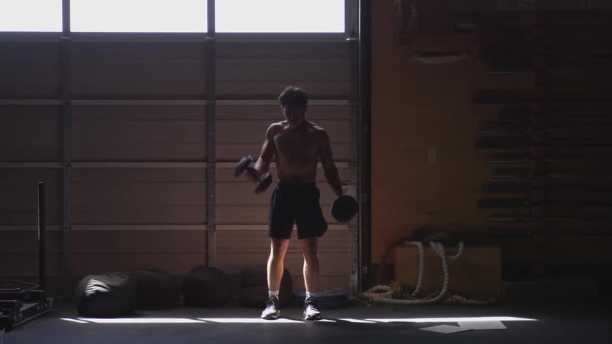 A muscular man lifts weights in a gym