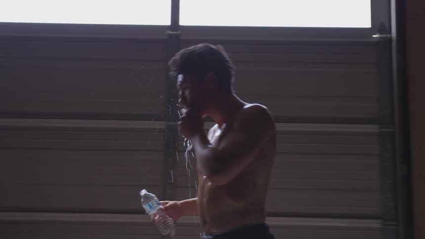 Shirtless man pours water over himself