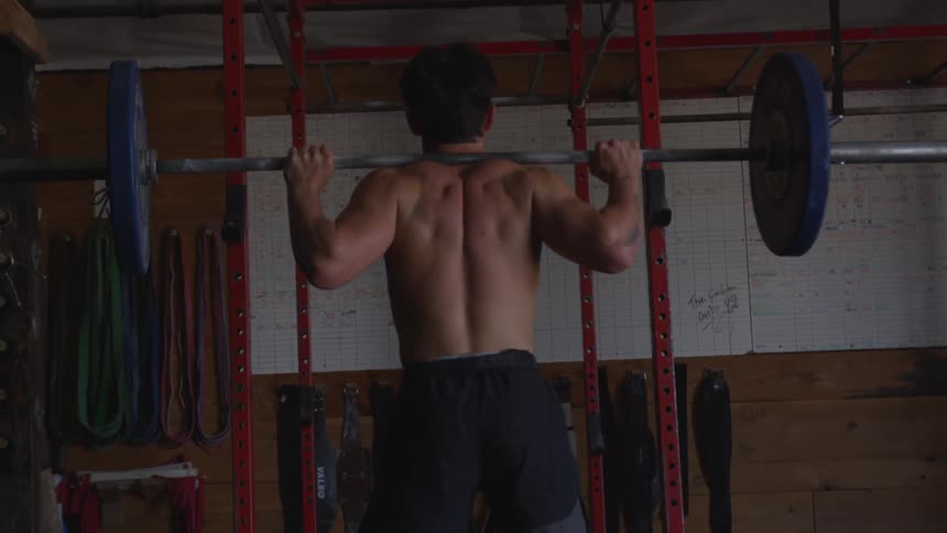 A young man squats with weights