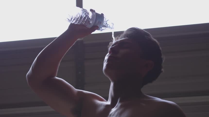 Half naked sweaty drinks water and freshens up indoors during daylight