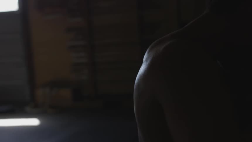 Light shines off a mans back in a dark room