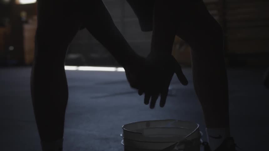 A person brushes off chalk from their hand to a bucket