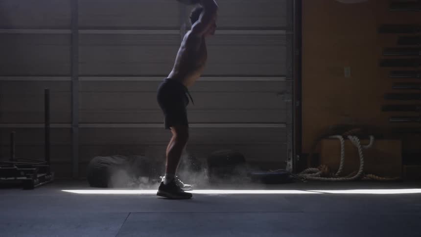 A young black man bounces a medicine ball in a dusty room