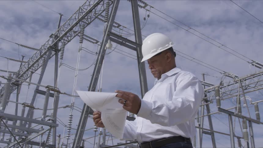 Man in a hard hat looking at plans on a power plant site