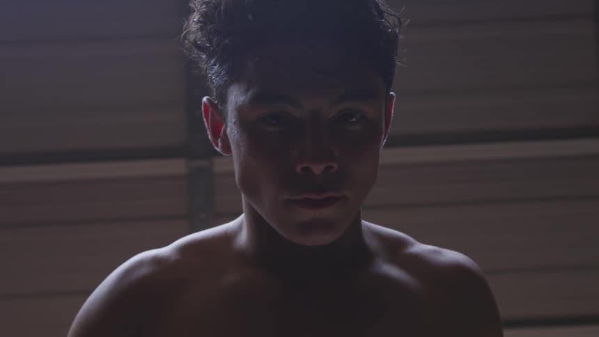 A young boy stands shirtless