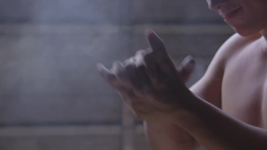 Shirtless young man claps powder off of hands