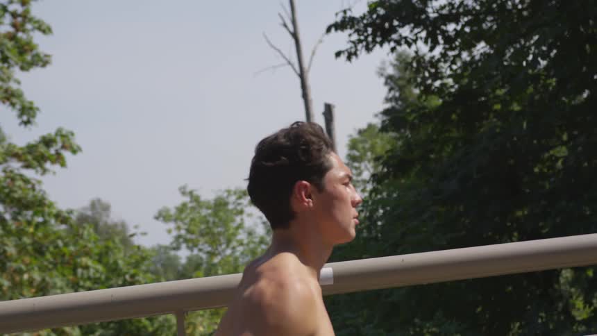 Shirtless man jogging on a bridge