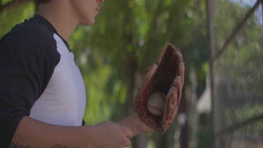 A man tossing a baseball and catching it with a baseball glove