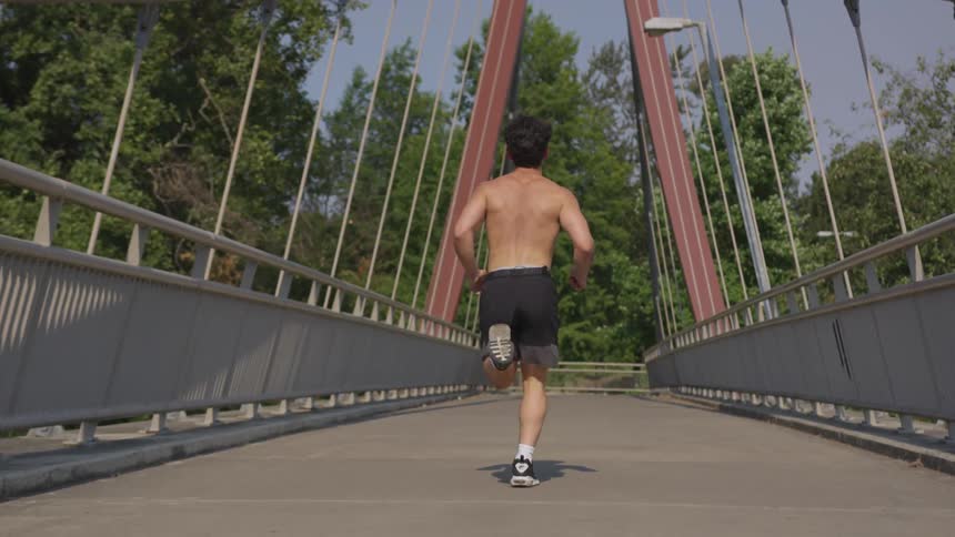 Fit and strong man jogging down bridge