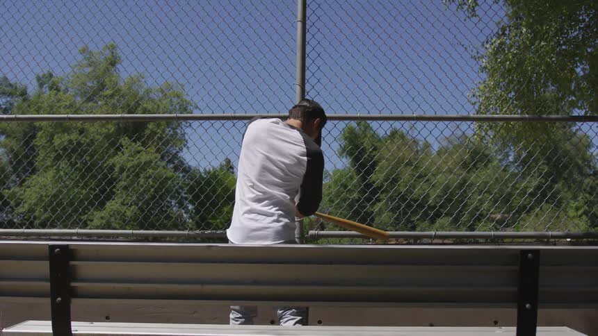 A white man swings a wooden baseball bat